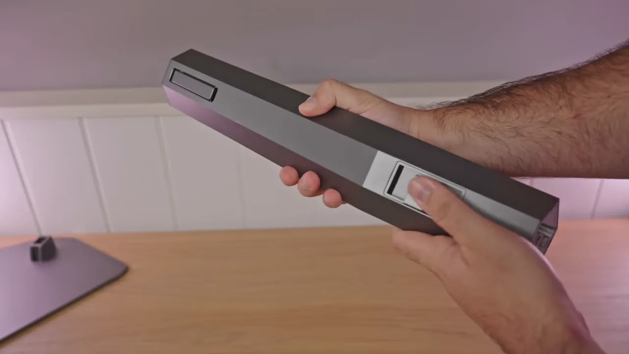 Mano mostrando la base del AOC AGON AG326UD sobre escritorio, detalle del anclaje de la peana