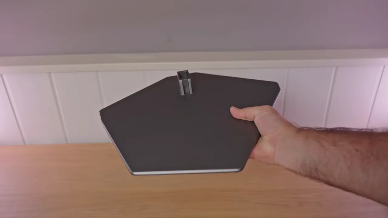 Vista de la peana del AOC AGON AG326UD sobre una mesa, con la mano señalando el anclaje