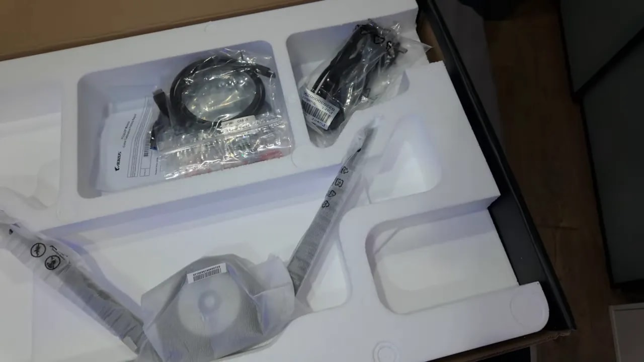 Cables y componentes del AORUS FO32U2P en la bandeja de la caja, durante el unboxing