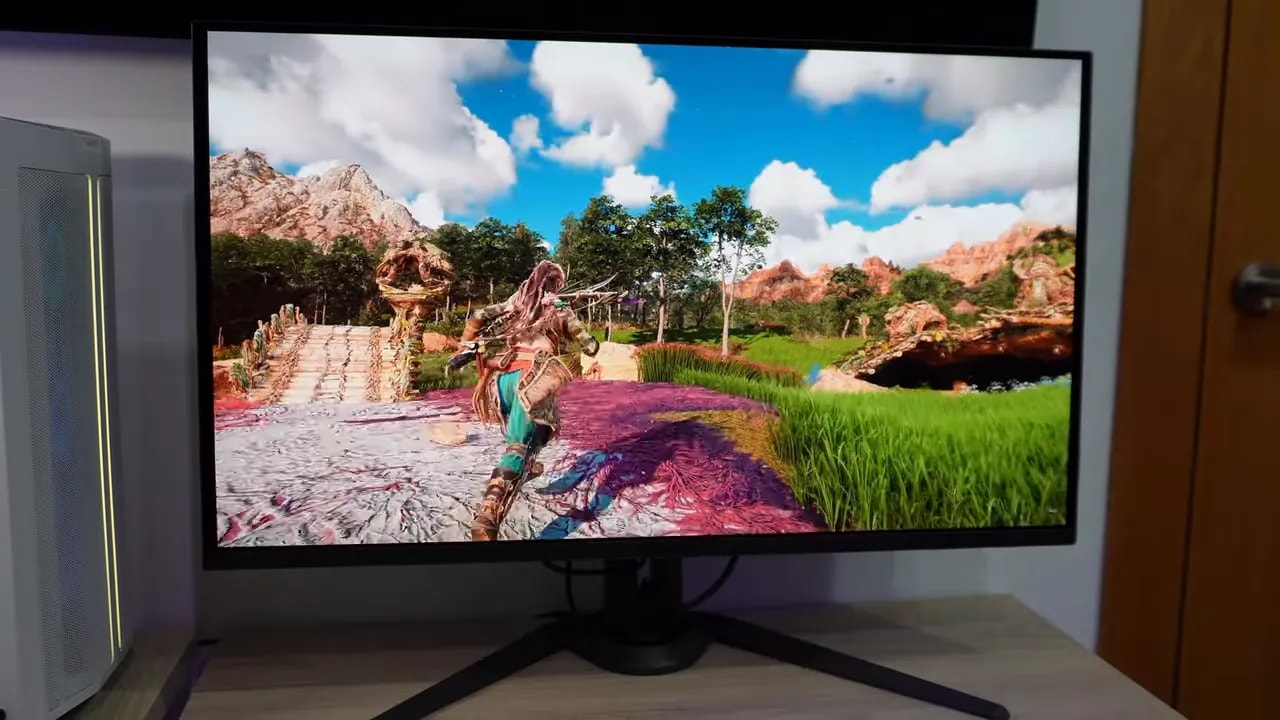 AORUS FO32U2P en escritorio mostrando gameplay con vegetación y terreno detallado