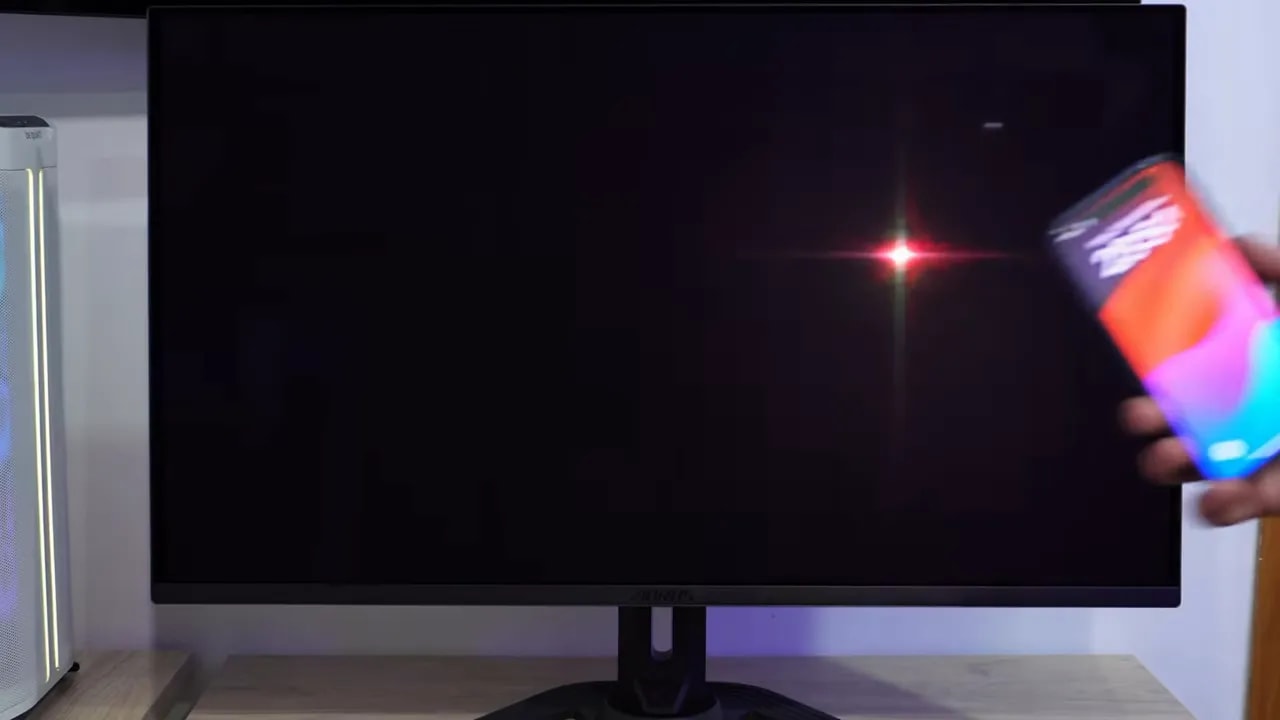 Monitor AORUS FO32U2P QD-OLED glossy con reflejos de luz apuntando hacia la pantalla