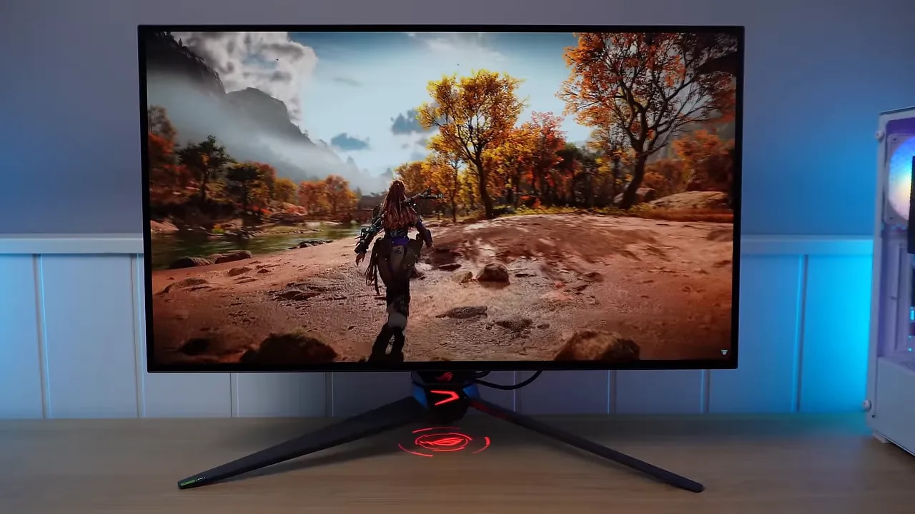 Monitor ASUS OLED mostrando gameplay en una mesa con iluminación ambiental