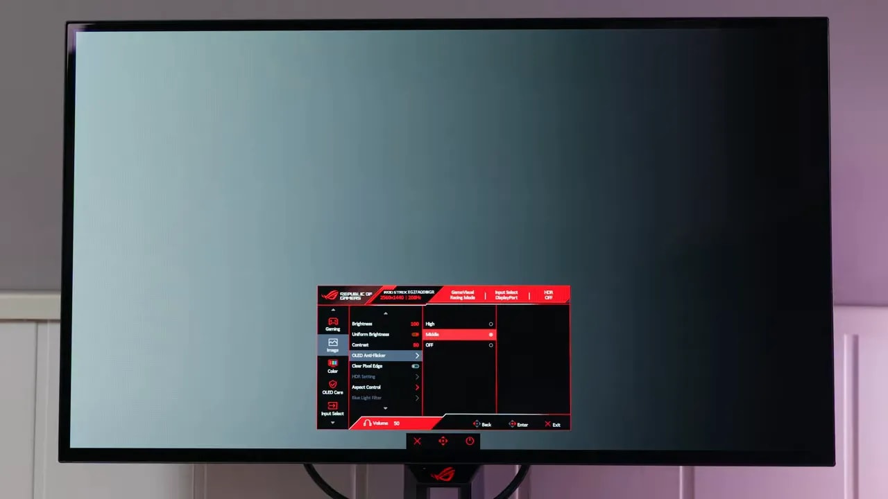Pantalla del ASUS ROG XG27AQDMGR encendida en un escritorio con luz ambiental