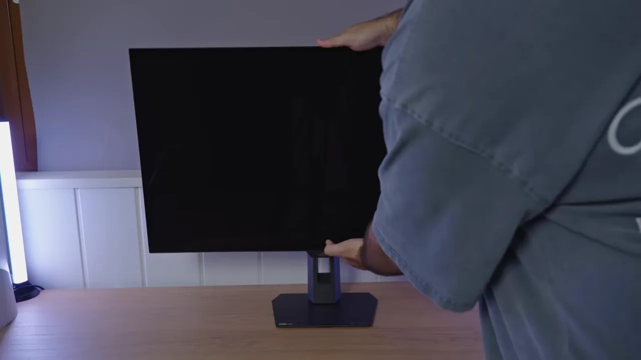 Monitor ASUS ROG XG32UCWMG con la peana en el escritorio mientras se ajusta su posición
