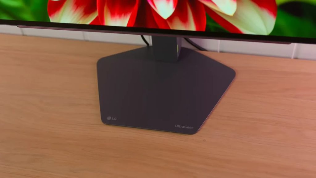 LG 27GX704A-B monitor base on the desk, with the UltraGear logo visible