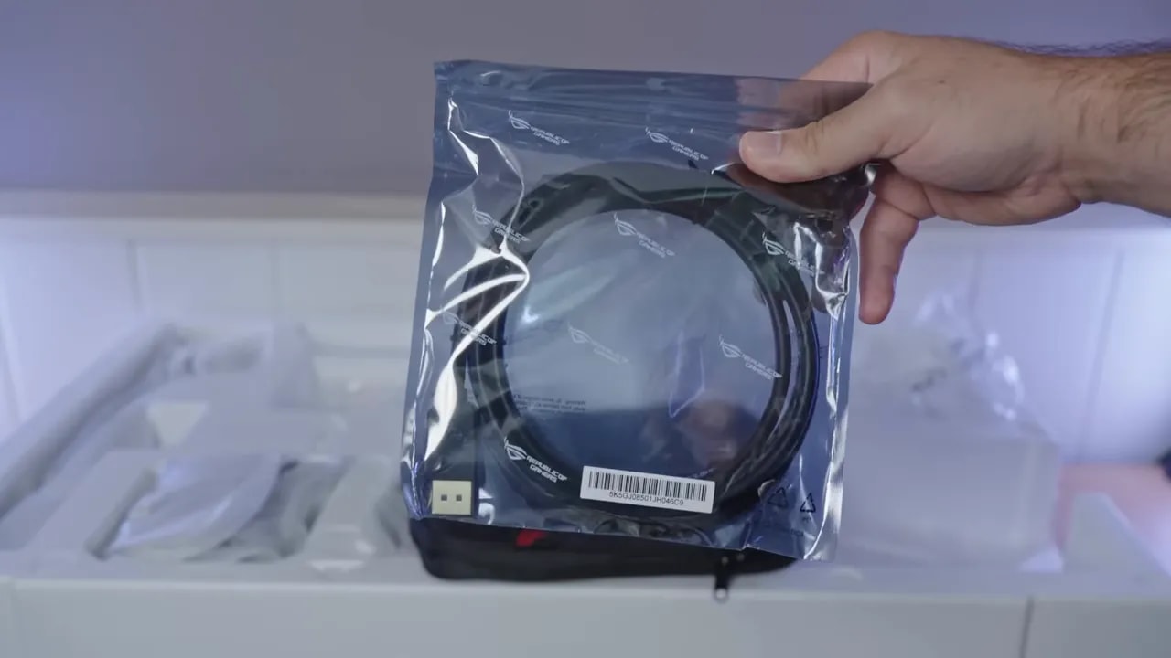 Cable del ASUS ROG XG32UCWMG en su embalaje durante el unboxing