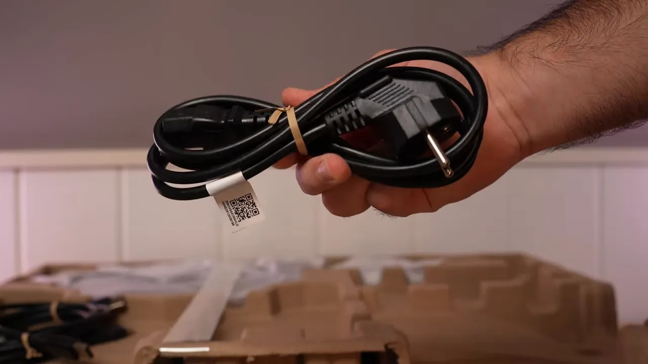 Mano mostrando un cable incluido en la caja del monitor AOC Q27G4ZE
