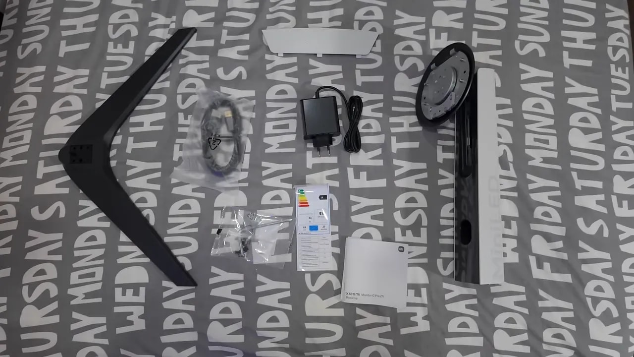 Contenido de la caja del Xiaomi Mini LED G Pro 27i sobre una mesa con cables, peana y manuales