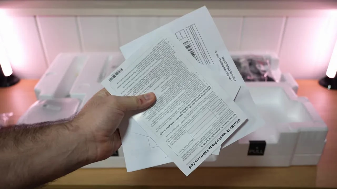 Mano revisando documentación y papeles del Gigabyte MO27Q28G durante el unboxing