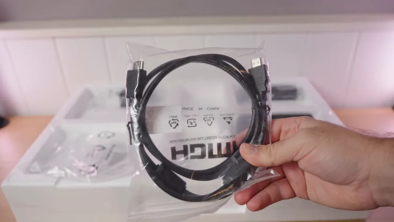 Fuente de alimentación y cables del monitor KTC H27T27 en la mano durante la revisión de accesorios
