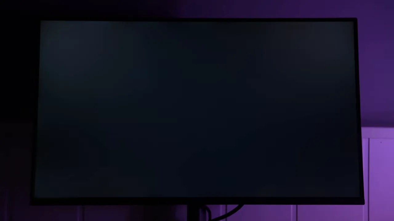Pantalla del monitor Gigabyte G25F2 encendida con luz ambiental púrpura en habitación oscura