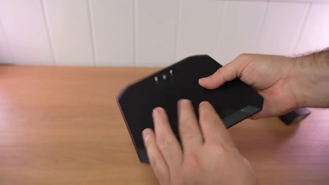 Manos mostrando la base o tapa de la peana del monitor Gigabyte GS27U