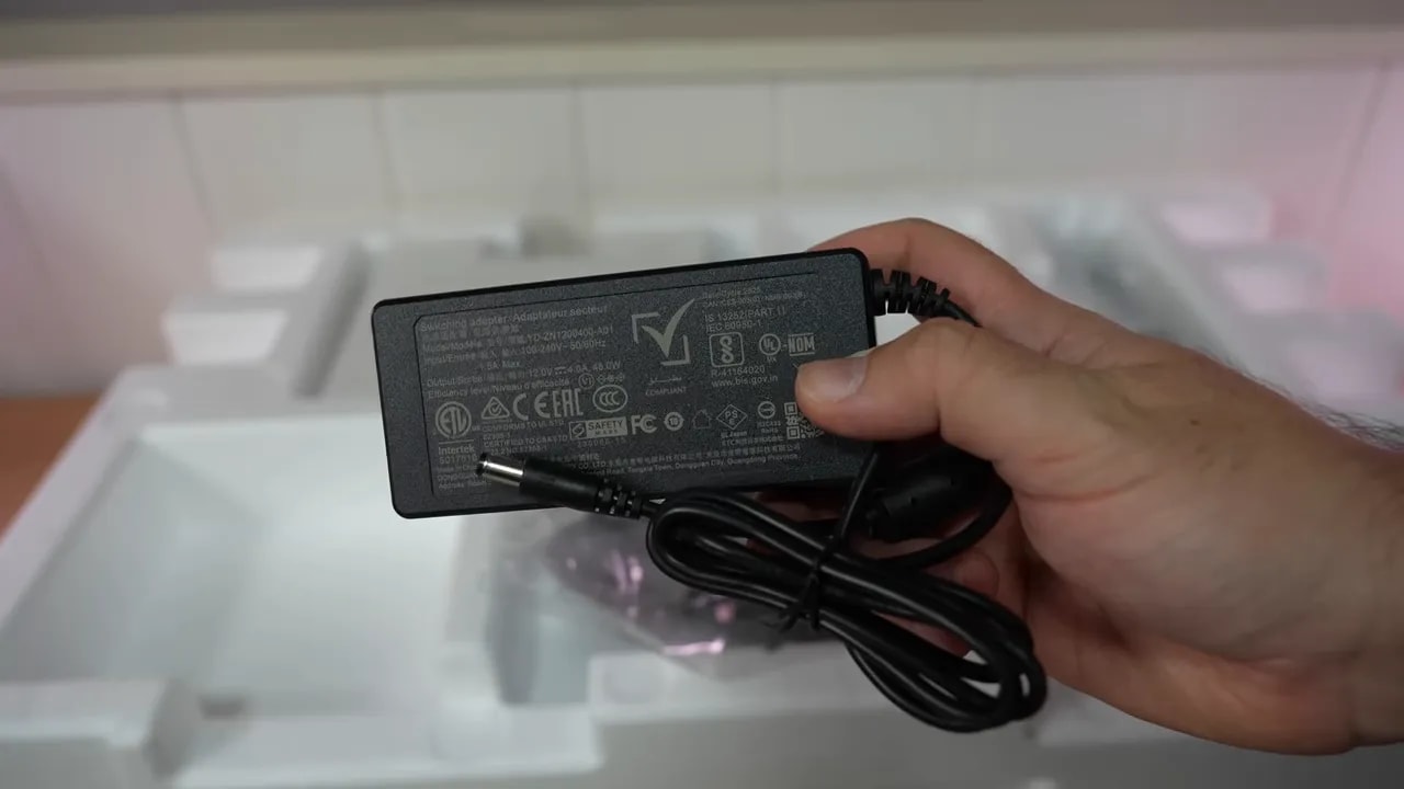 Mano conectando el cable de alimentación al adaptador del monitor KTC H27T27