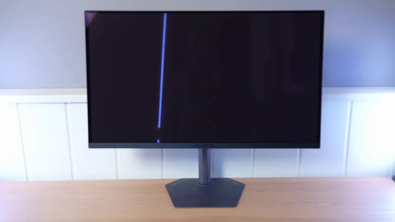 Monitor QD-OLED con acabado glossy mostrando una línea de luz azul en un entorno iluminado