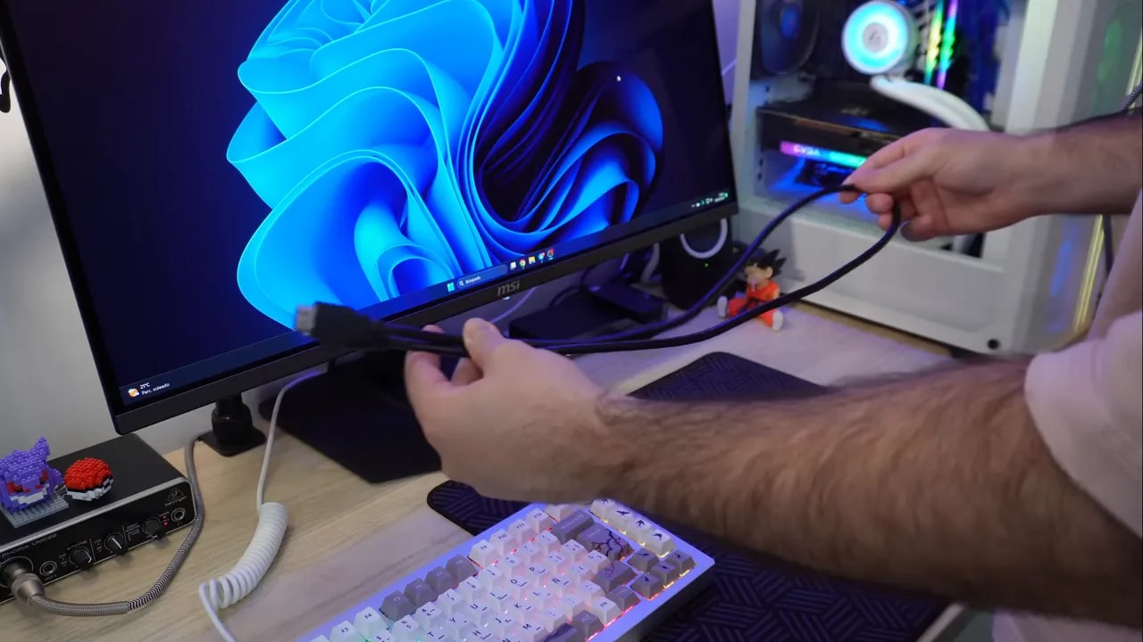 Conector HDMI/DisplayPort y manos ajustando el cable trasero en el MSI MPG 321URX