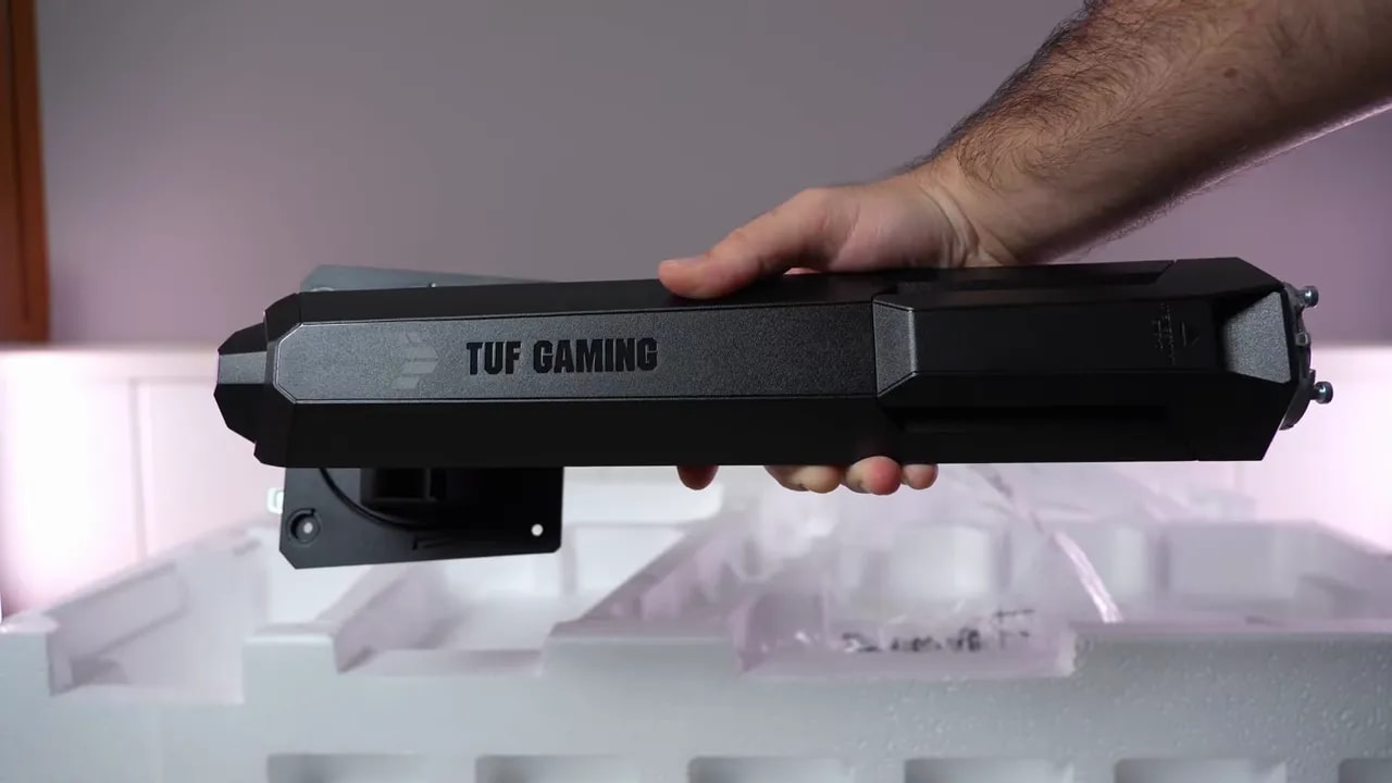 Parte delantera inferior del monitor ASUS TUF VG27AQL5A durante el montaje, con mano sujetando el soporte