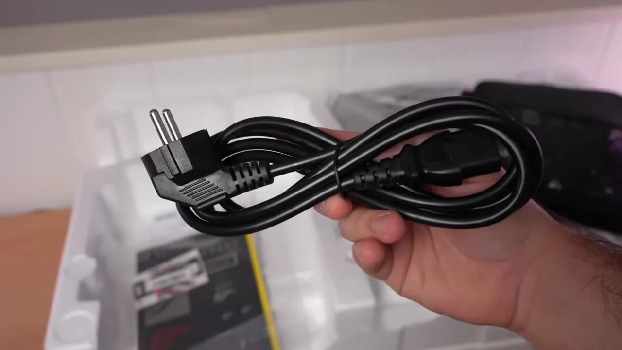 Mano mostrando la cubierta inferior y el soporte del monitor Asus ROG sobre la mesa