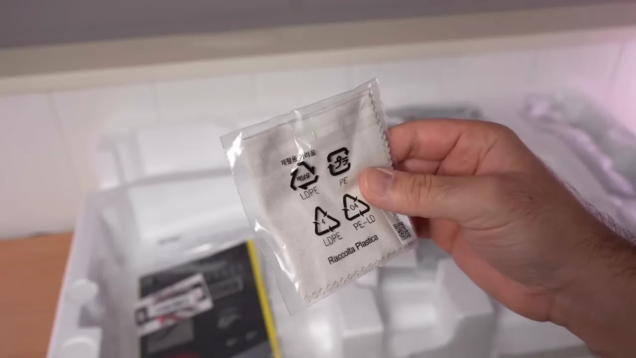 Mano mostrando la cubierta inferior y el soporte del monitor Asus ROG sobre la mesa