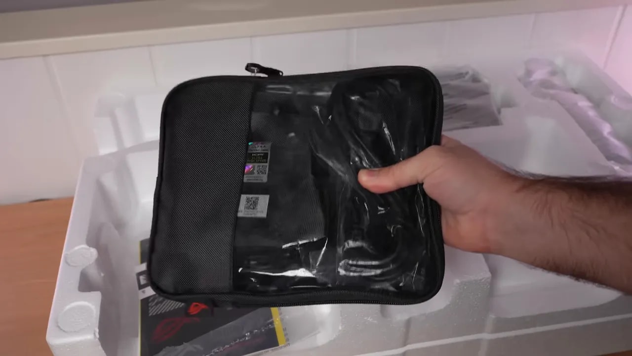 Mano mostrando la cubierta inferior y el soporte del monitor Asus ROG sobre la mesa