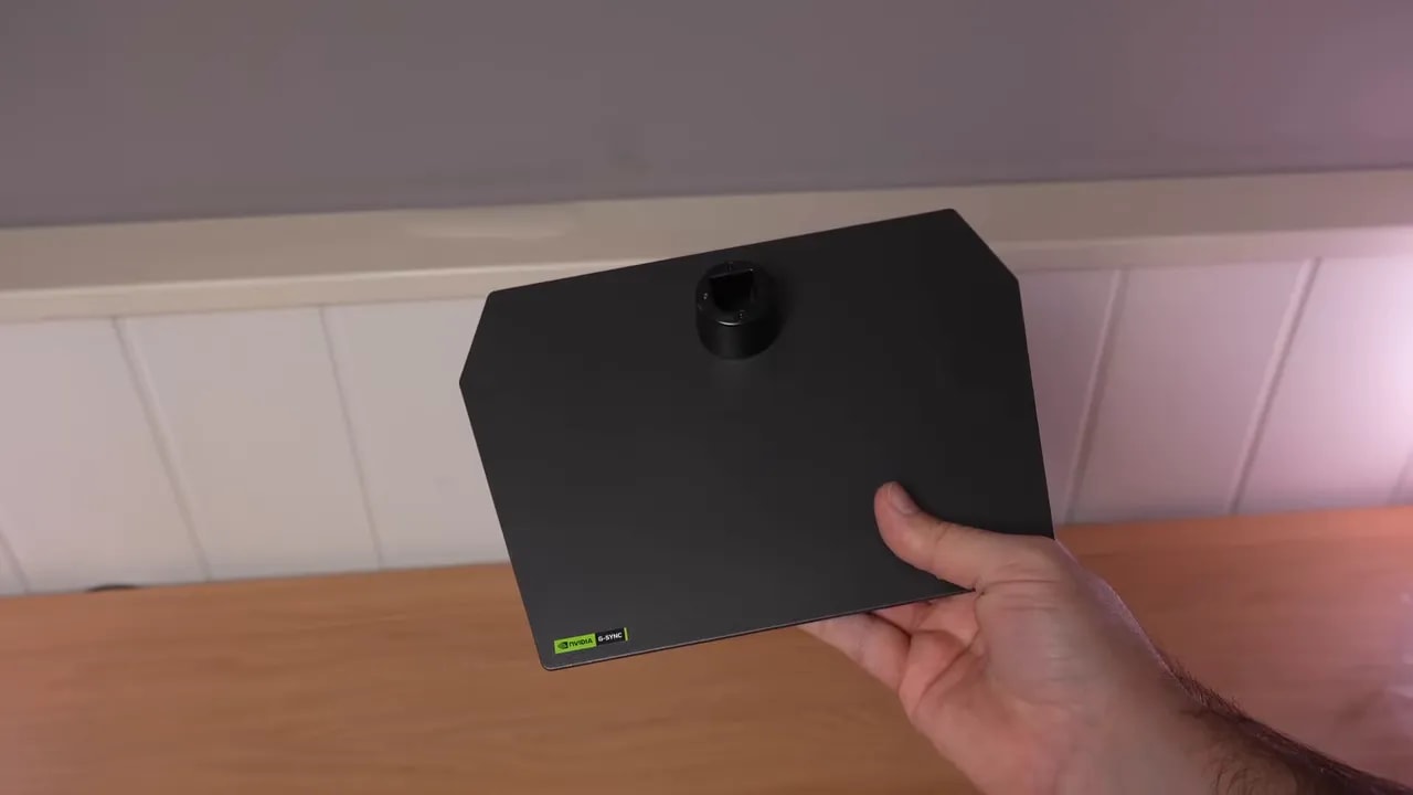 Mano mostrando la cubierta inferior y el soporte del monitor Asus ROG sobre la mesa
