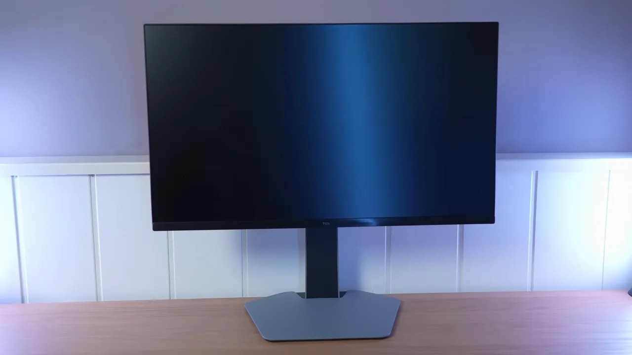 Vista frontal del TCL 25G64 en escritorio con pantalla mate y soporte de base
