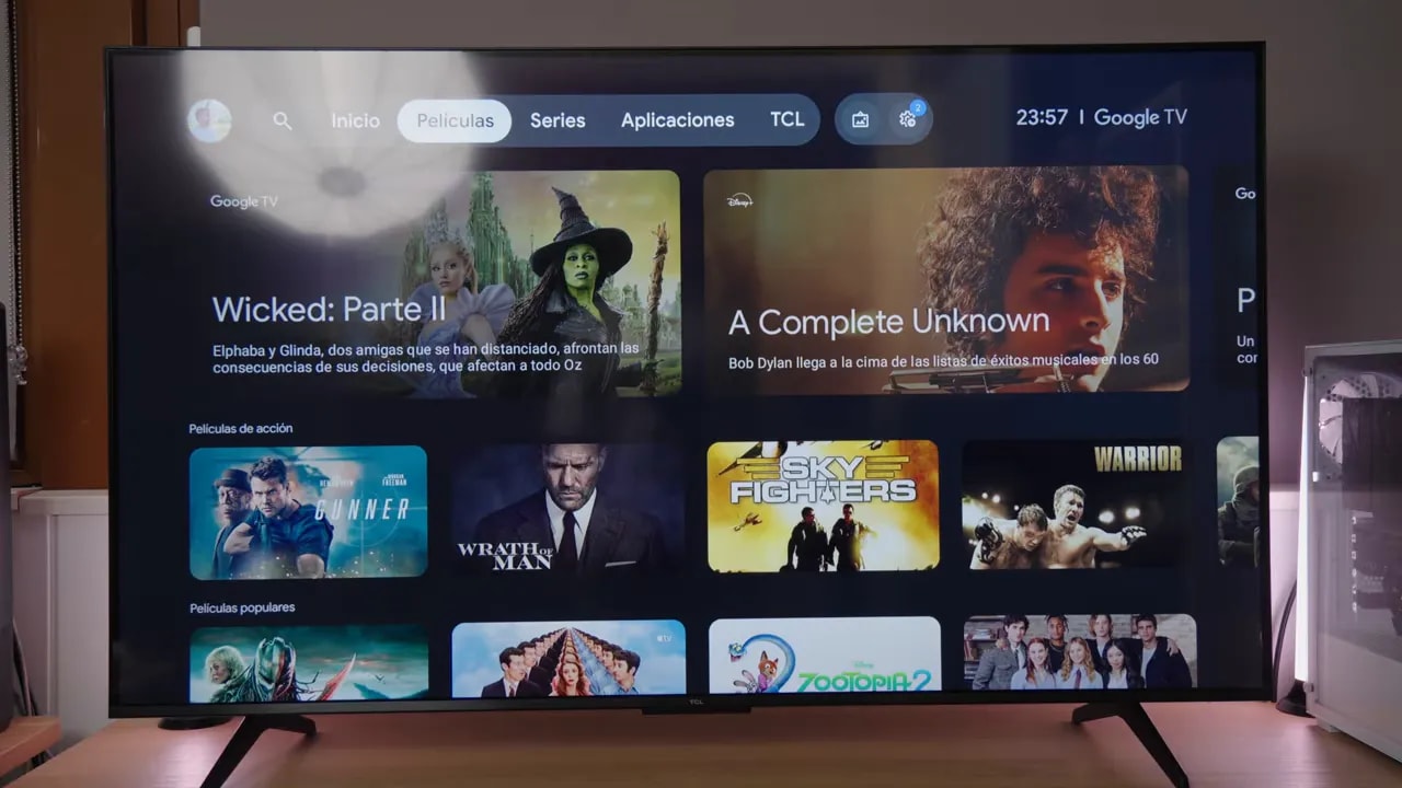 TCL C6K mostrando la interfaz de Google TV en una sala, con enfoque en el acabado y posibles reflejos